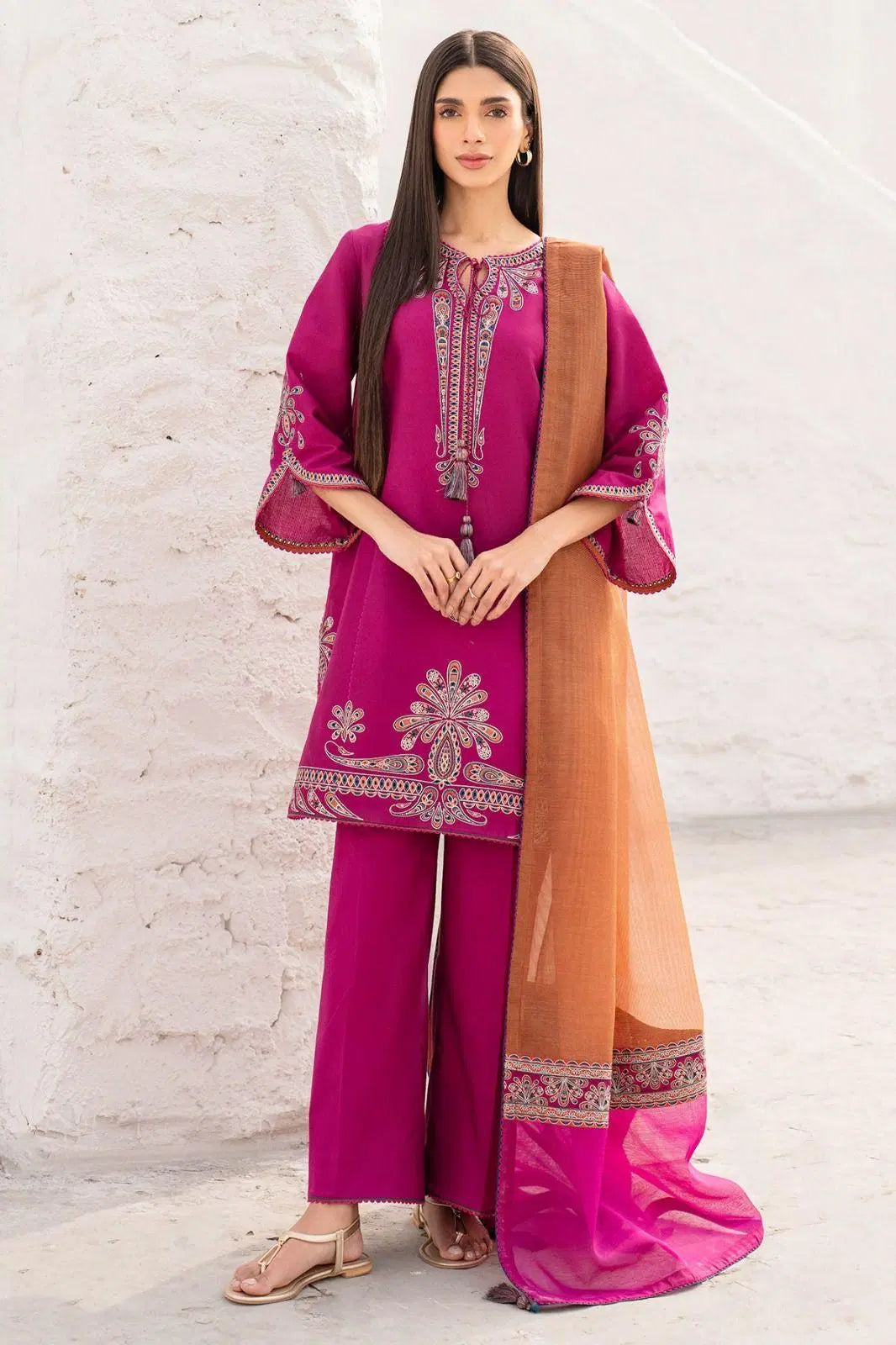 Look loom women wearing a pink 3 piece embroidered suit set with intricate designs and an orange dupatta