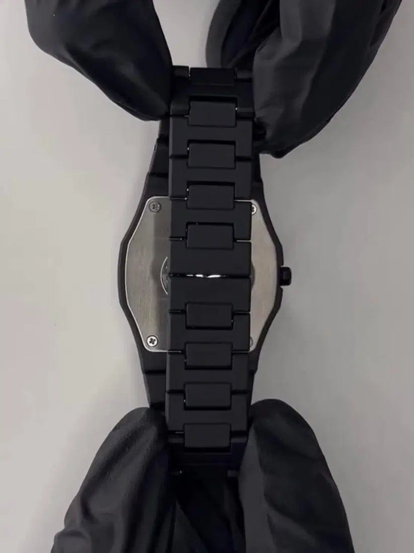 Look loom black unisex quartz analogue watch showing the back case and bracelet held by gloved hands