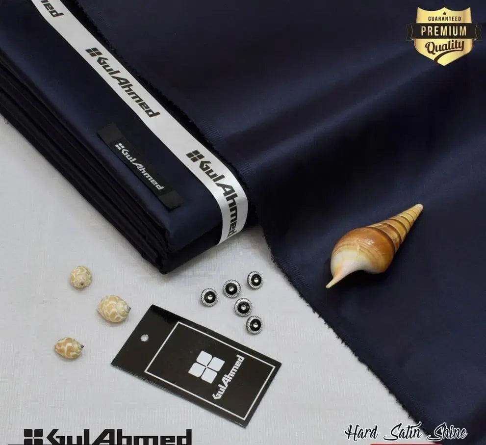 Navy blue hard satin fabric roll with Gul Ahmed label buttons tags and seashell props for men’s unstitched cotton suit