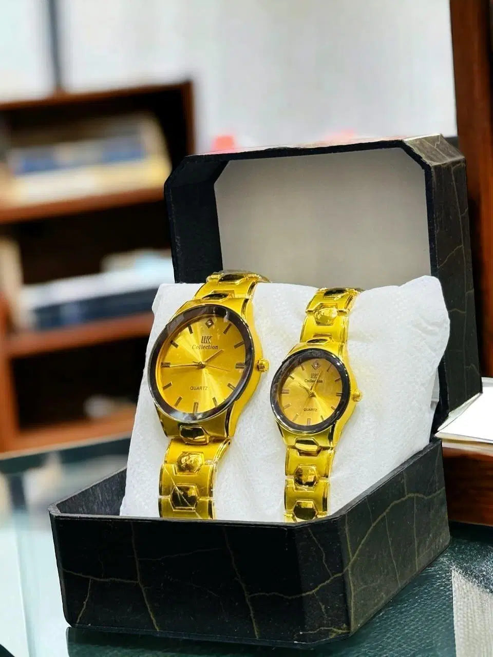 Look loom matching couple watches in gold with elegant round dials displayed in a black gift box